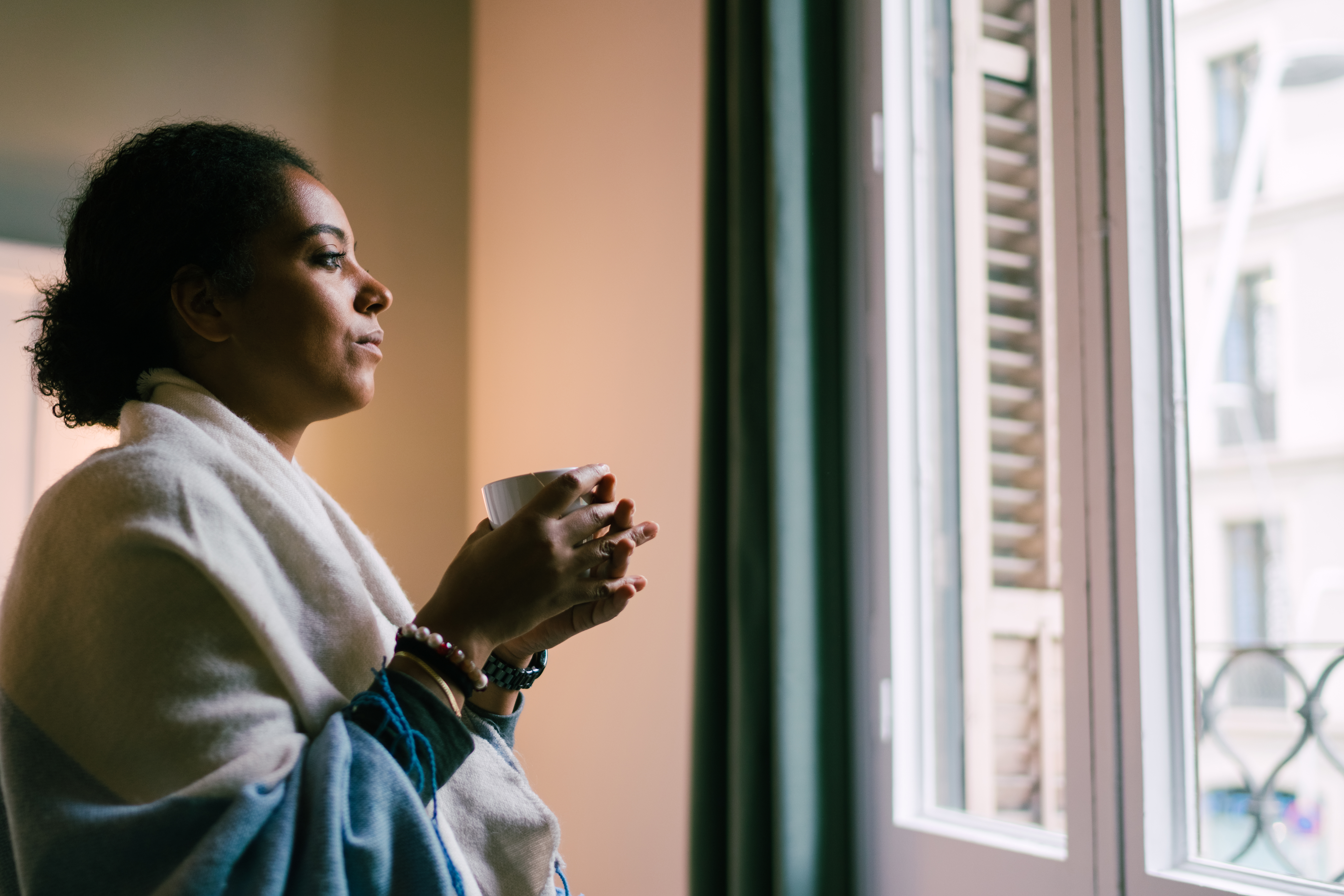 Woman Looking Through Window With A Cup Of Tea Via Getty Credit Martin Dm